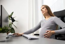 side-view-pregnant-businesswoman-her-desk-holding-her-belly_23-2148804400-6569163